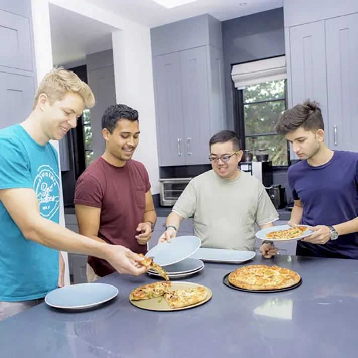 A group of Best Buddies Living roommates with and without IDD eating pizza in their kitchen