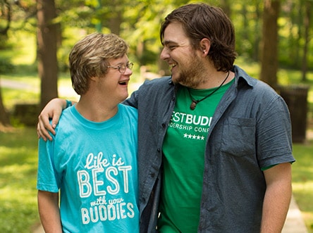 College_program Two male College buddy pairs. Peer buddy has his arm the shoulder around his Buddy.