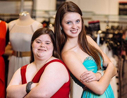 Two female High school students standing back to back and smiling