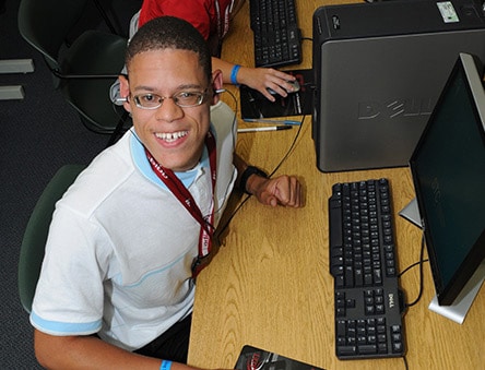 A male ebuddies participant sitting at a computer with a smile on his face