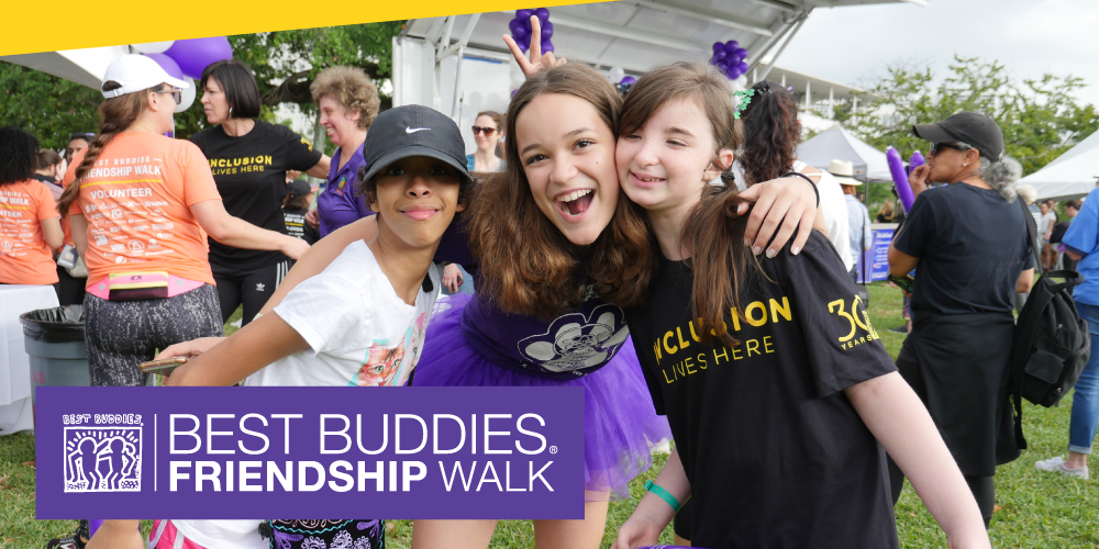3 Best Buddies participants huddled at a Best Buddies Friendship Walk