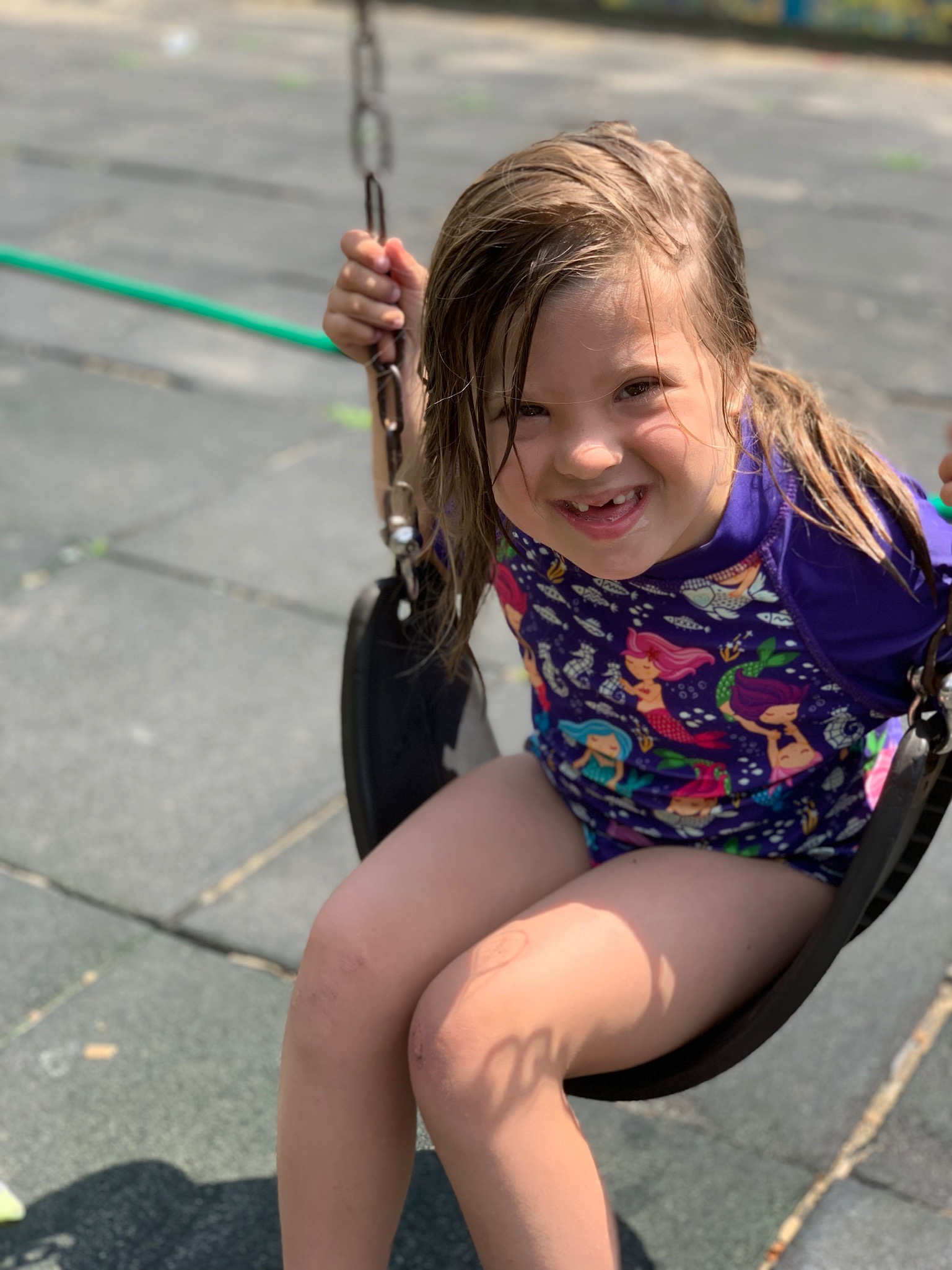 young girl with Down syndrome in a bathing suit on a swing