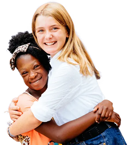 Two female Best Buddies Middle School participants hugging with smiles on their faces