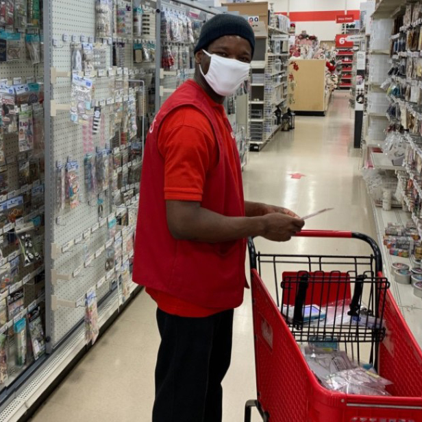 Best Buddies Jobs Participant Joseph Parker working in retail store holding a red shopping cart