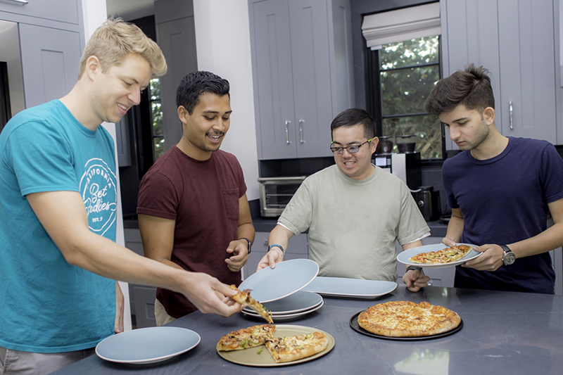 A group of 4 Best Buddies roommates eating pizza