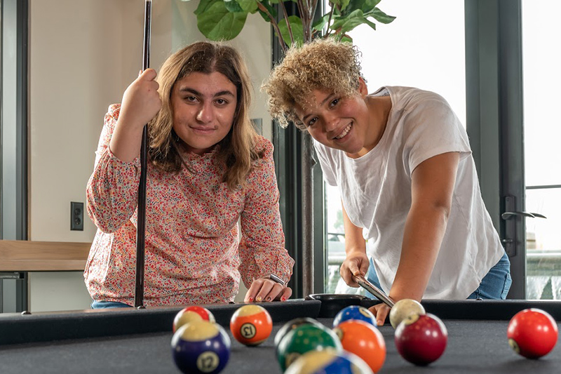 Two female Best Buddies Living participants playing pool