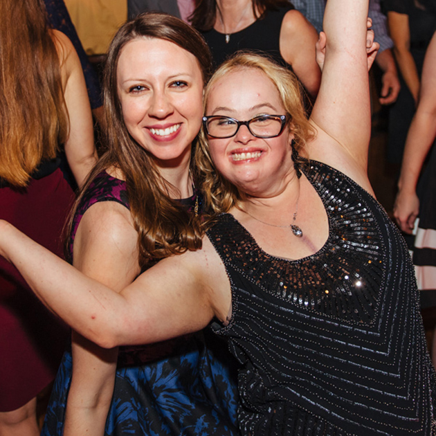 Buddy Pair participants matched in 2010, Olivia DeCaria and Kristen Starcher smiling and dancing in a crowd