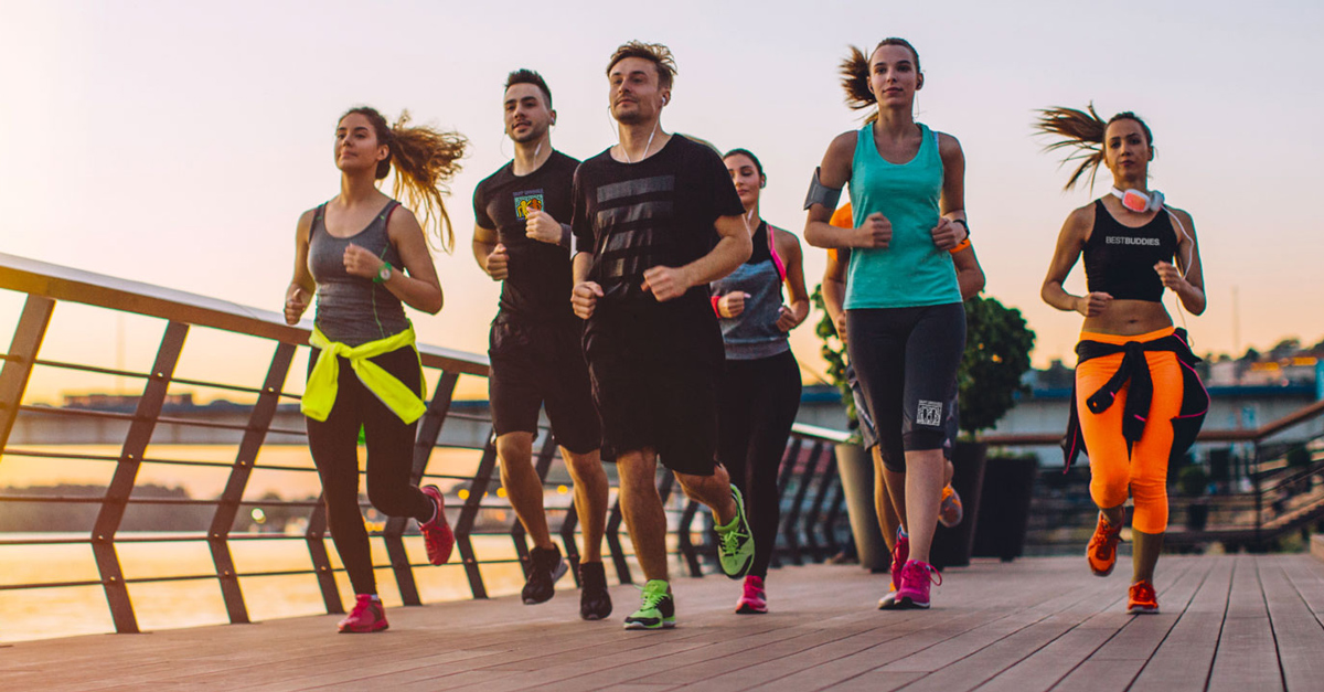 A group of runners jogging on a boardwalk