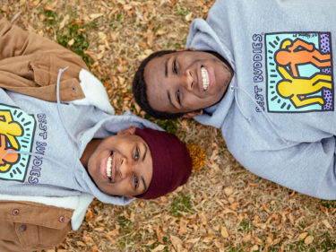 Two African American teenagers smiling in Best Buddies hoodies