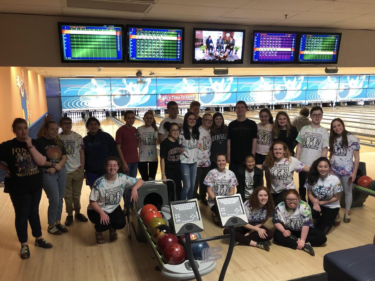 large group of Best Buddies members smile together at a bowling alley