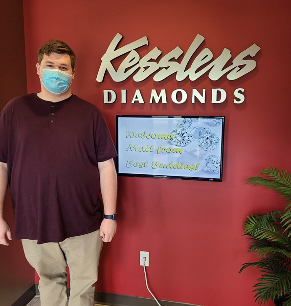 Matt, Best Buddies Jobs participant in Wisconsin, posing next to the Kesslers Diamonds logo