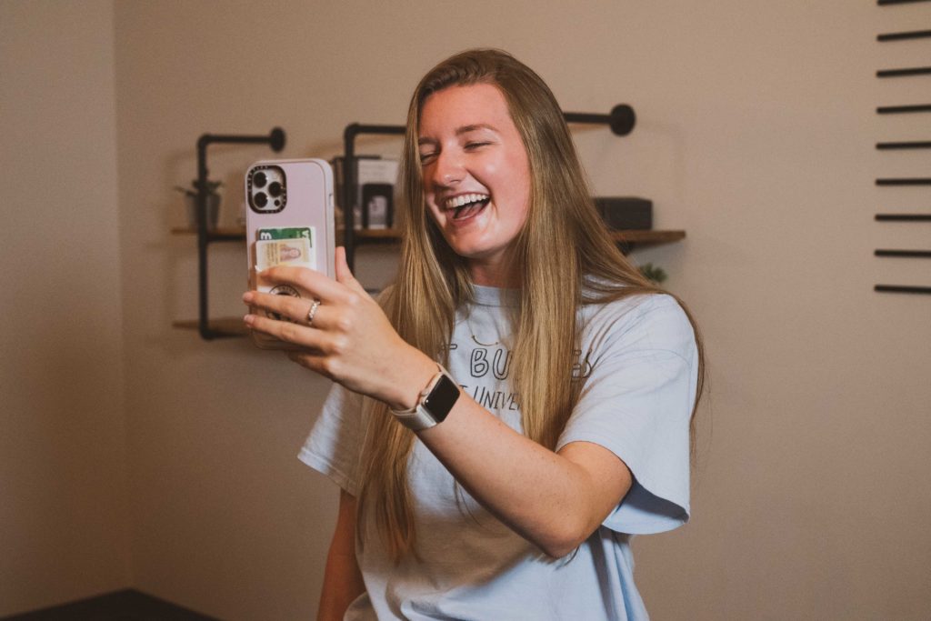 Rhode Island Member Young woman smiling and looking at her phone