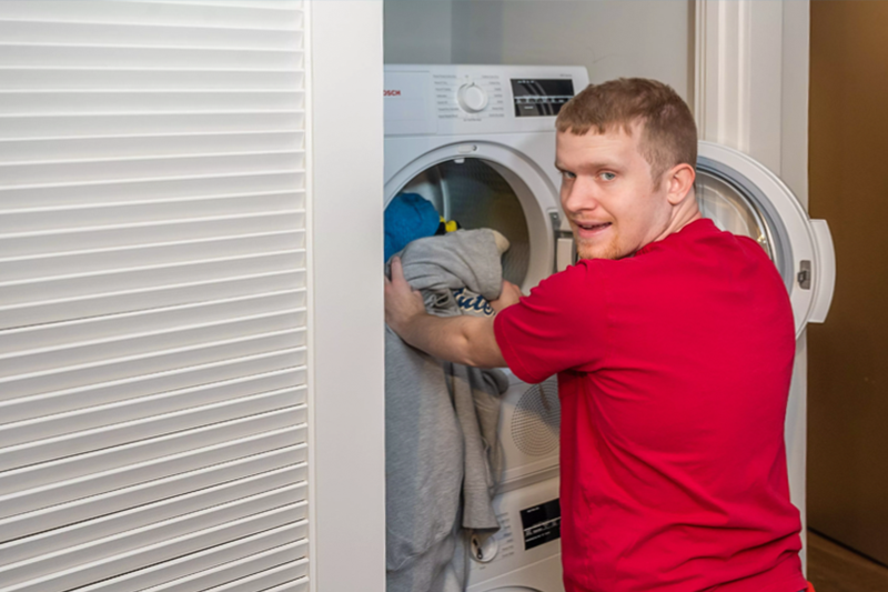 A Best Buddies Miami Living Program male Participant is doing his laundry.