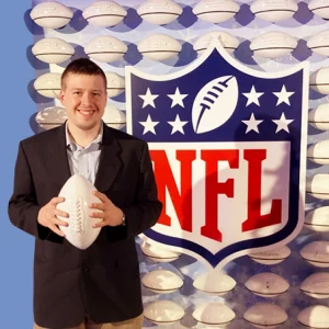Jobs Participant, Zack Smith is holding a white football next to an NFL sign.