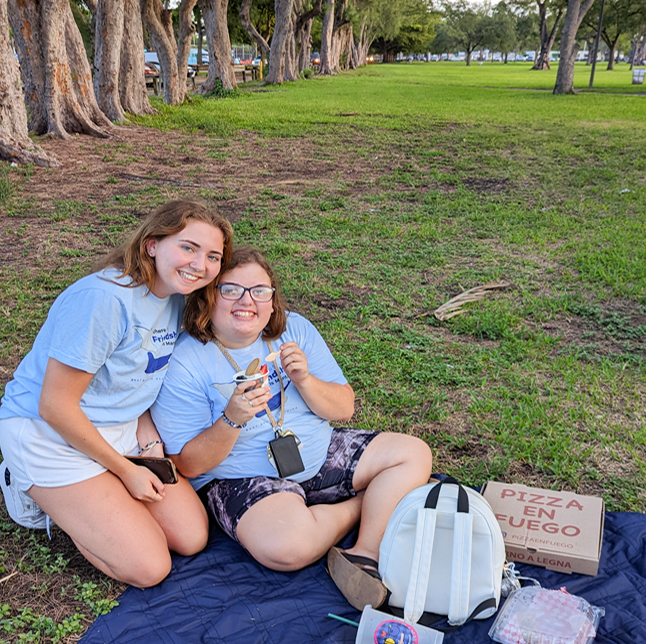 Two Best Buddies Living participants picnic in a wooded area.
