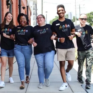 A group of Best Buddies Program participants walk down the street, arm in arm.