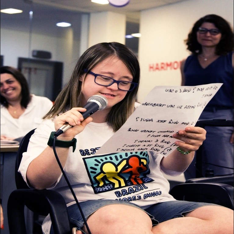 A Best Buddies program participant is reading while speaking into a microphone.
