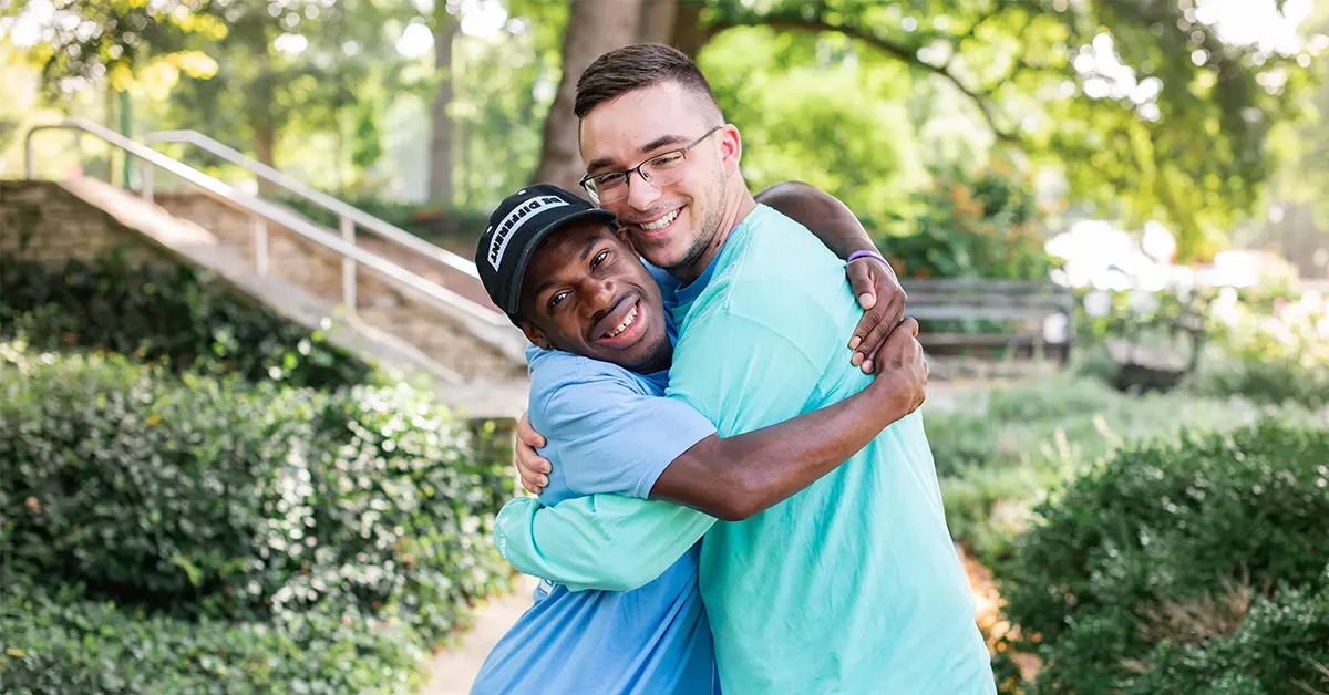 Two male Best Buddies participants hugging