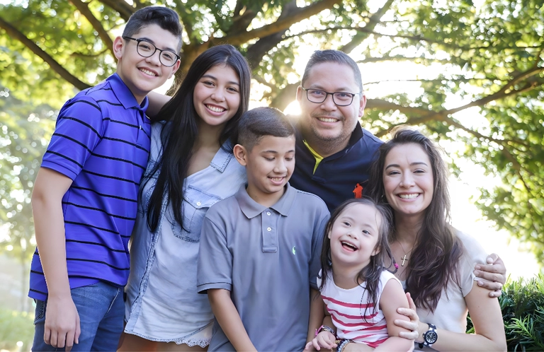 Michelle Aventajado and her family stand beneath a verdant tree, their smiles radiating warmth and joy.