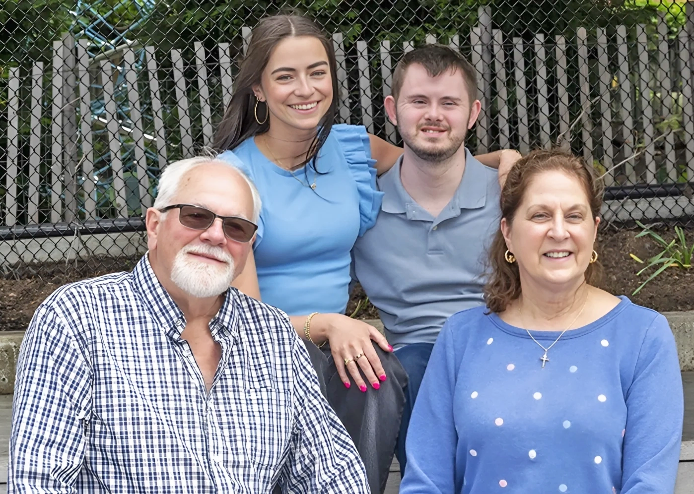 Mentor and mentee with family members smiling together outdoors.
