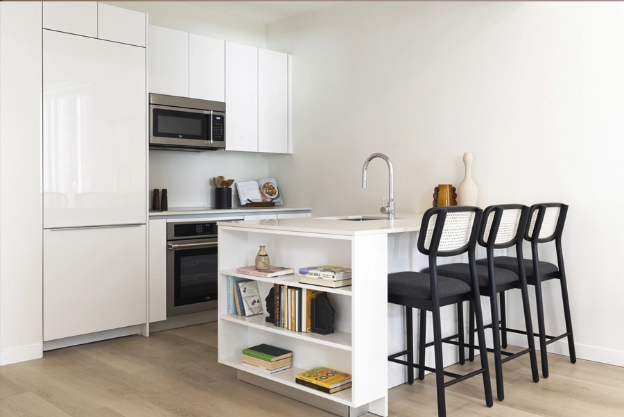 Living - NY, NY SoMA Kitchen Modern white apartment kitchen with island seating, stainless steel appliances, and minimalist design.