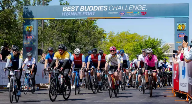 Cyclists ride through the Best Buddies Challenge: Hyannis Port starting line during the annual fundraising event supporting inclusion for people with intellectual and developmental disabilities.