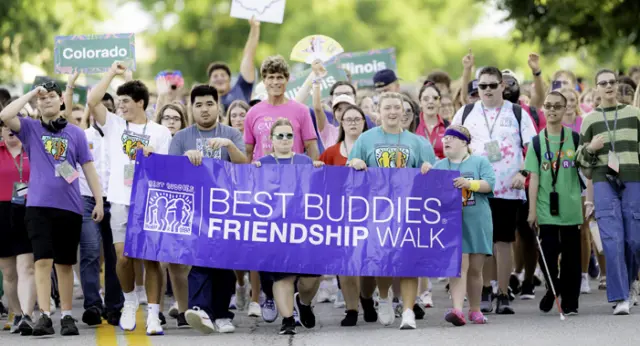 Participants of all abilities lead the Best Buddies Friendship Walk, carrying a Best Buddies Friendship Walk banner while supporters from across the country follow behind.