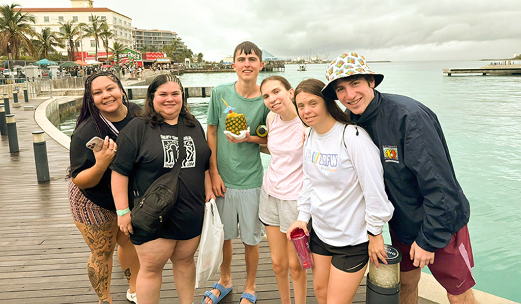 2027 BB Travel Bahamas Trip Group of Best Buddies participants and volunteers posing together by the waterfront in the Bahamas during an inclusive travel adventure.