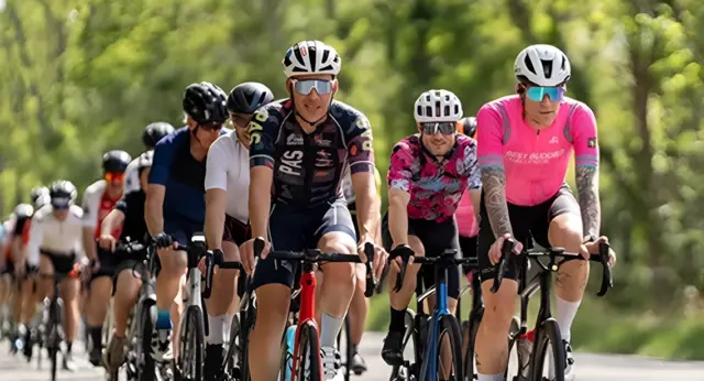 Cyclists riding together along a tree-lined route during a Best Buddies Challenge.