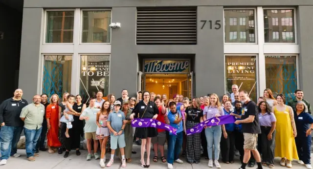 Best Buddies participants and supporters celebrating with a ribbon cutting outside The Standard residential building.