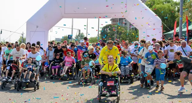 News - North Macedonia Launch Post image 1 Best Buddies participants and supporters cross the starting line of an outdoor Friendship Walk as colorful confetti fills the air.